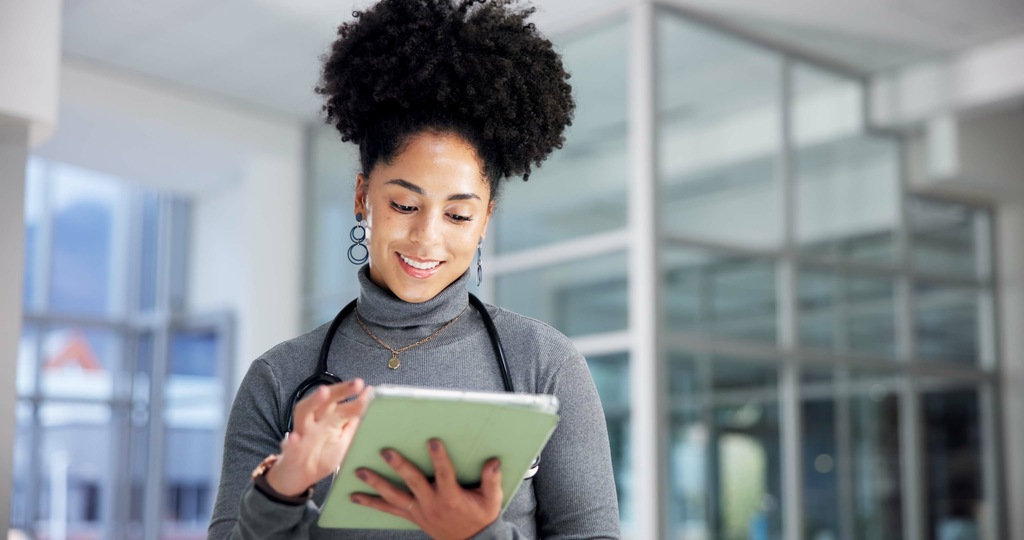 Profissional de saúde utilizando tablet em ambiente corporativo representando terceirização de TI para gestão de sistemas e suporte tecnológico.