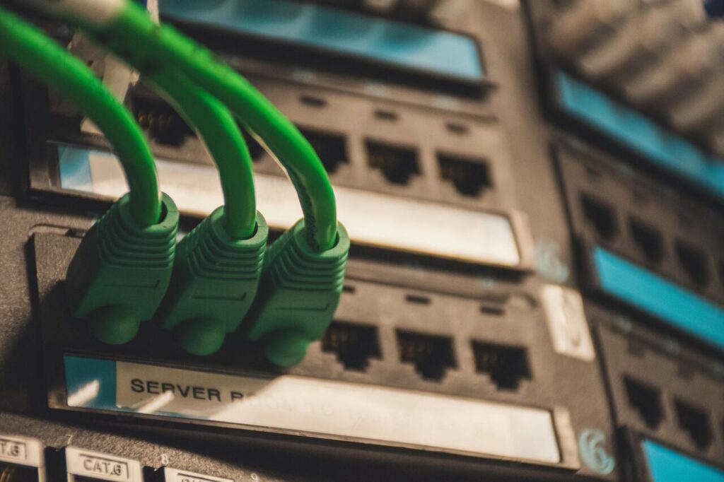 Cabos de rede verdes conectados a servidores representam data centers e consumo energético da infraestrutura de TI.